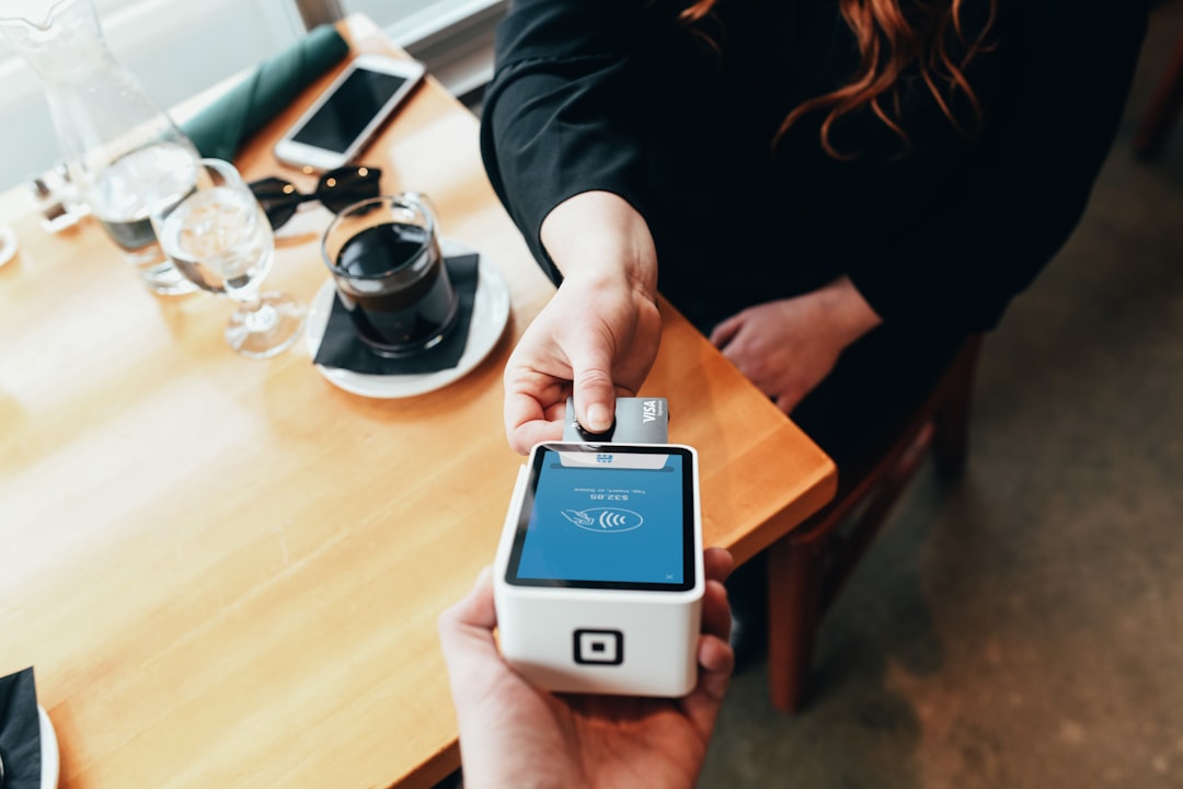 Person holding a modern credit card payment terminal device for secure electronic transactions in business environment
